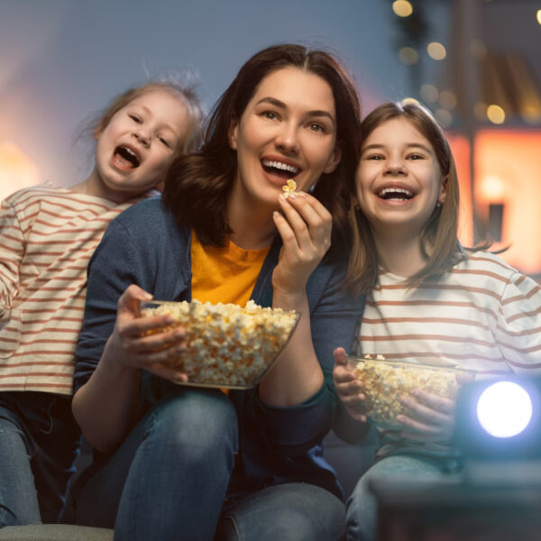 Mother and daughters enjoy watching movie and eating popcorn